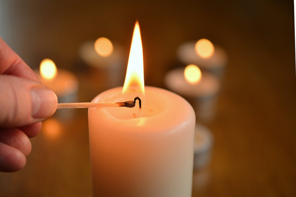 Lighting pillar candle with tealights in background